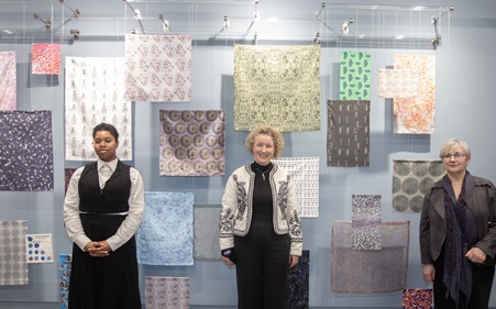 Women in front of hanging fabrics